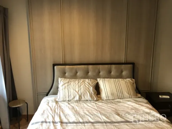 Condominium for rent in Pathum Wan, Bangkok - Cozy bedroom with upholstered headboard, neutral tones, and bedside tables.