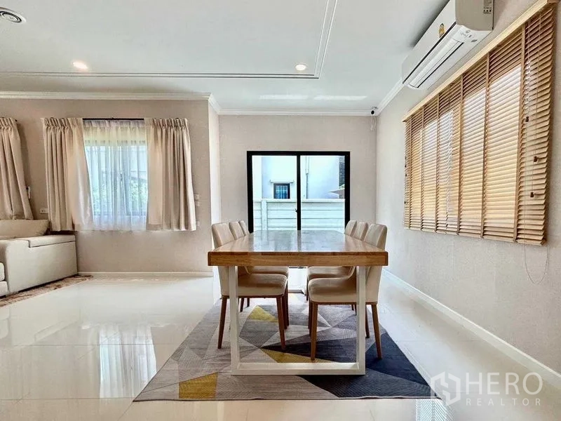 独立式住宅 出租在Khlong Sam Wa, Bangkok - 餐区配四人木桌，宽窗百叶与露台推拉门