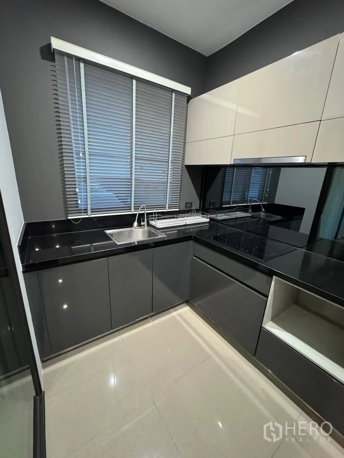 Townhouse for rent or sale in Lat Phrao, Bangkok - Full view of L-shaped kitchen with glossy cabinets and sink.