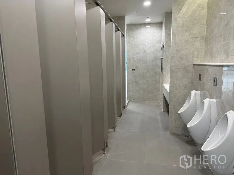 สำนักงาน ให้เช่าในRatchathewi, Bangkok - โถงห้องน้ำมีห้องสุขาเป็นแถว โถปัสสาวะ ผนังลายหิน และไฟสว่าง