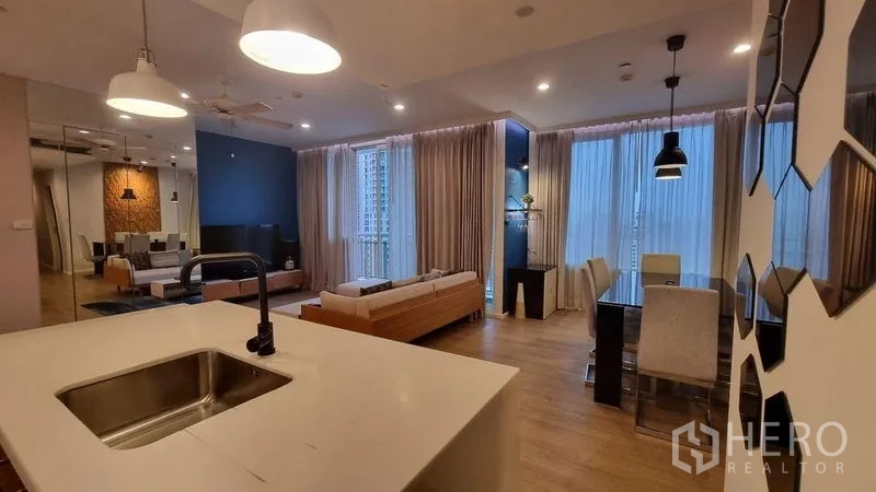 公寓 出租在Watthana, Bangkok - 现代开放式厨房带岛台水槽，面向餐厅与客厅的大窗。
