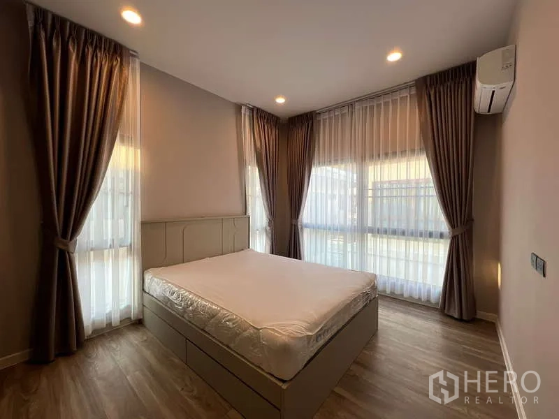 Detached House for rent in Bang Kapi, Bangkok - Corner bedroom with large windows, sheer curtains and air conditioner.