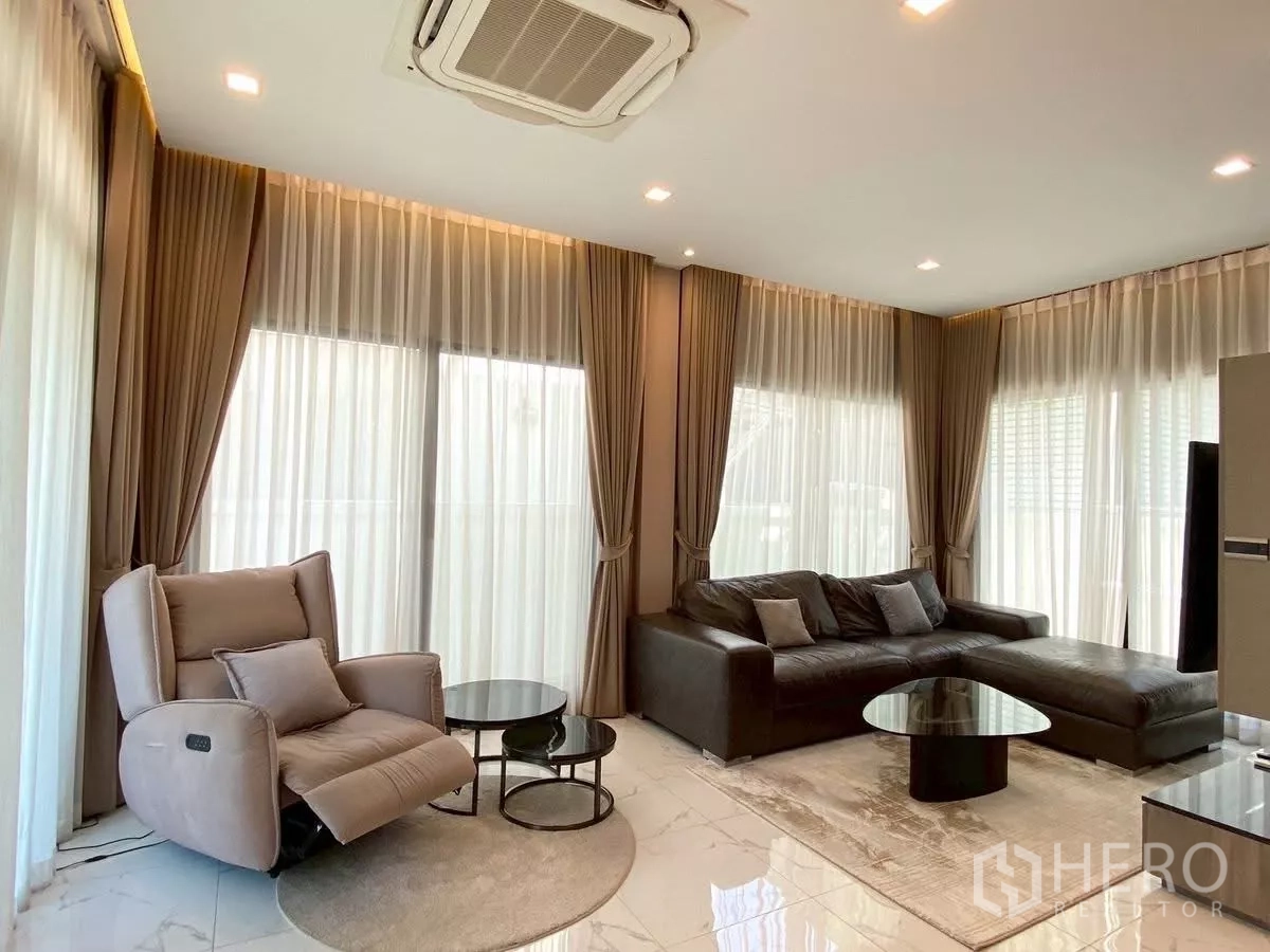 บ้าน ให้เช่าในBang Phli, Samut Prakan - มุมนั่งเล่นสว่าง โปร่ง ผ้าม่านเต็มผนัง เก้าอี้ปรับเอน โซฟามุม และแอร์ฝังฝ้า