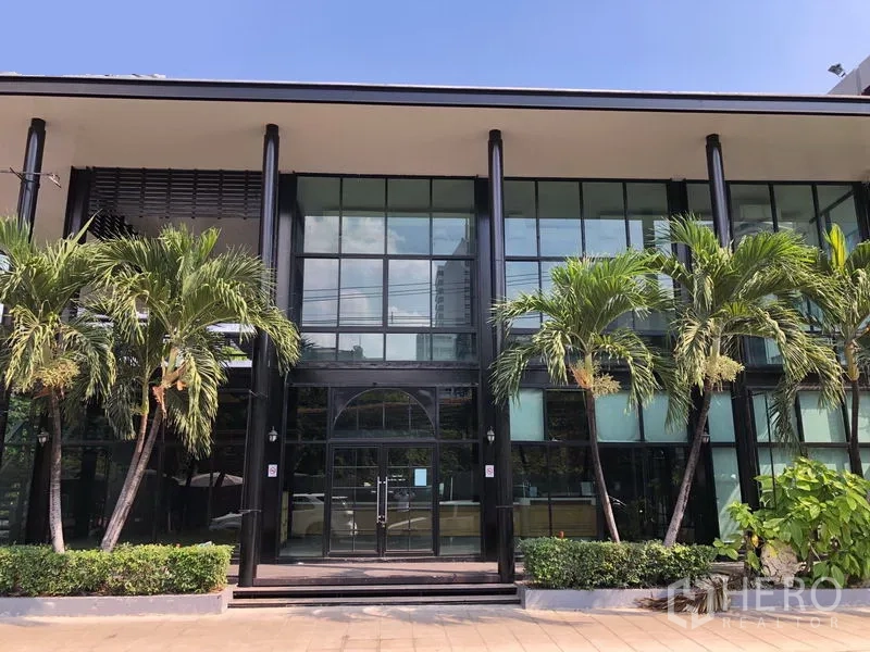 Retail Space for rent in Khlong Toei, Bangkok - Modern two-storey retail building with full-height glass facade and palm landscaping in Nana, Bangkok.
