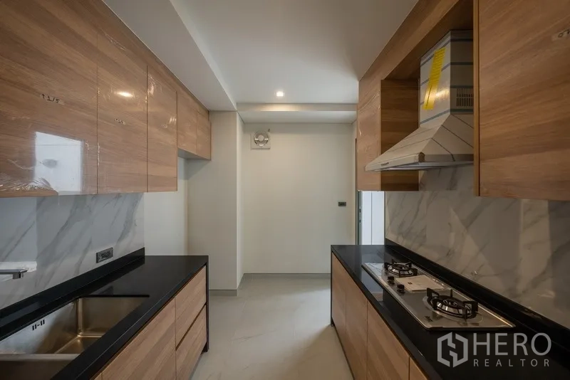 Detached House for rent or sale in Yan Nawa, Bangkok - Separate Thai kitchen with wood cabinetry, gas hobs and stone countertops.