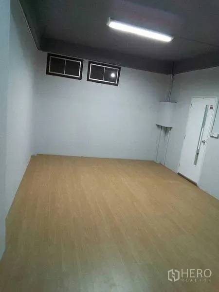 Shophouse for rent in Khlong Toei, Bangkok - Renovated empty room with light wood flooring and high ceiling, ideal for office use.