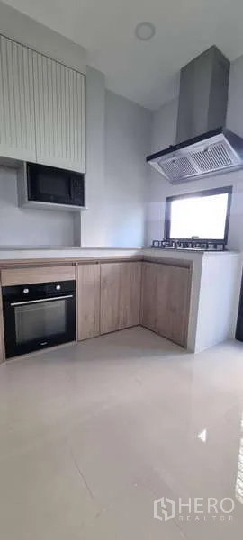 独立式住宅 出租在Lat Krabang, Bangkok - 嵌入式厨房，木质柜体、烤箱、燃气炉与排烟机。