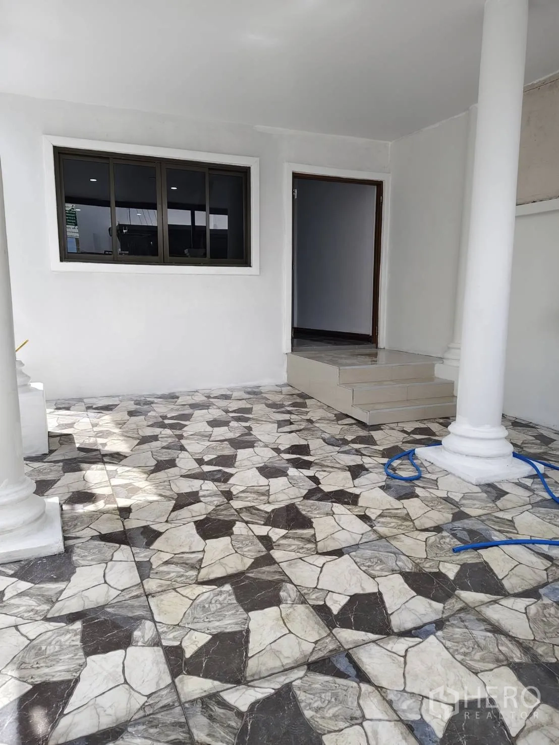 Townhouse for sale in Phra Khanong, Bangkok - Shaded front terrace with columns and patterned stone-look tiles.
