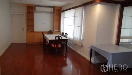 Condominium for rent or sale in Sathon, Bangkok - Bright dining area with table, built-in cabinetry, air conditioner, and large corner windows with sheer curtains.