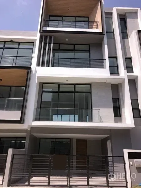 Townhouse for rent or sale in Saphan Sung, Bangkok - Modern multi-level townhouse facade with large glass balconies and a gated entrance.