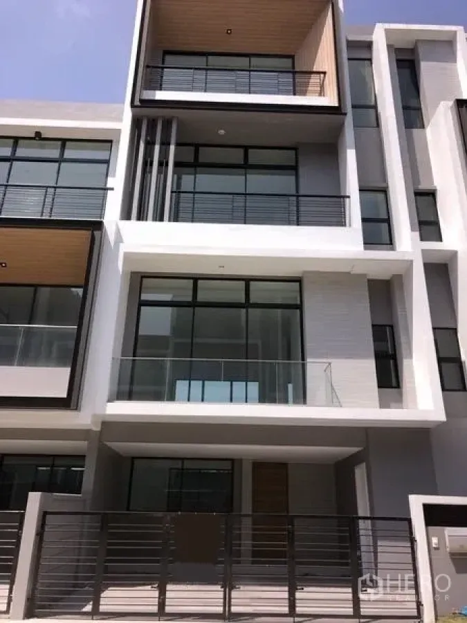 Townhouse for rent or sale in Saphan Sung, Bangkok - Modern multi-level townhouse facade with large glass balconies and a gated entrance.