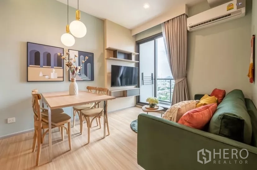 Condominium for rent in Chatuchak, Bangkok - Cozy living space with green sofa, floor-to-ceiling window and a four-seat dining table.