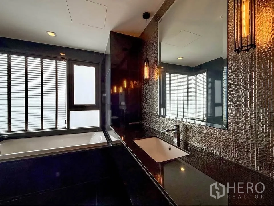 公寓 for rent in Khlong Toei, Bangkok - 浴室洗手台配马赛克墙与大镜面，可见浴缸与窗户。