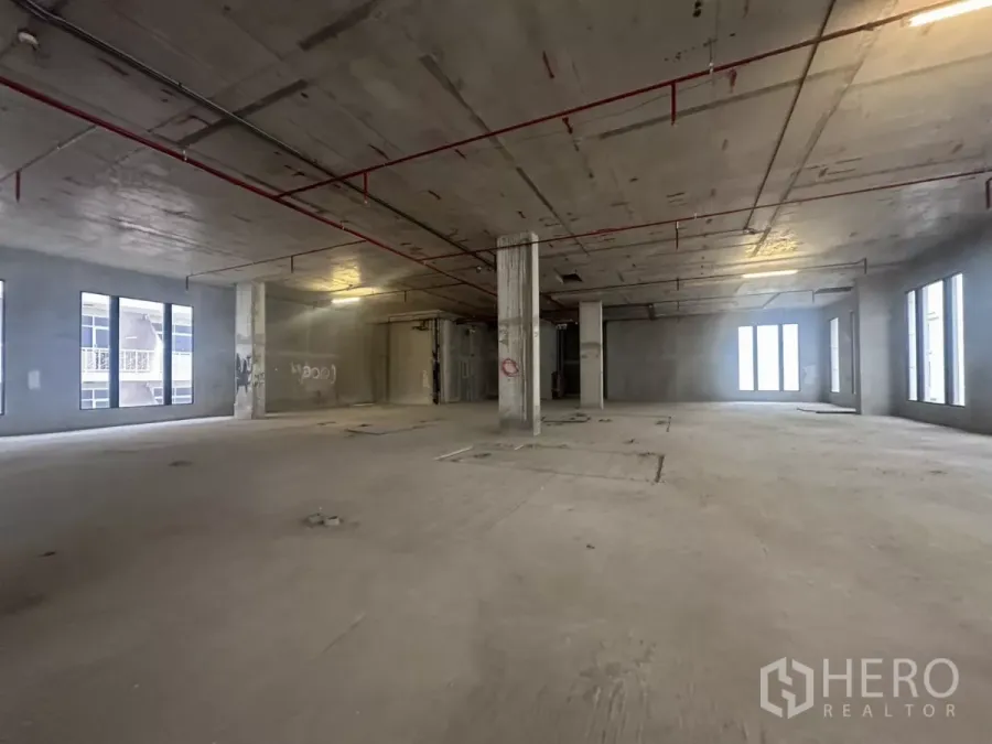 Retail Space for rent in Watthana, Bangkok - Unfinished open‑plan retail floor with concrete columns, high ceiling and long window lines.