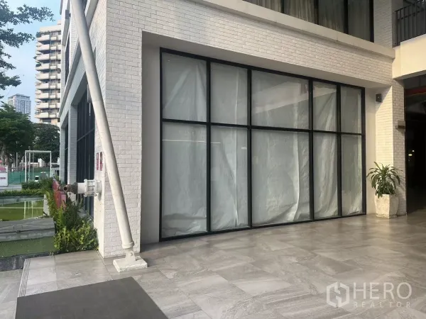 零售空间 出租在Khlong Toei, Bangkok - 临街立面，黑色框架的整面玻璃与室外石材地面。