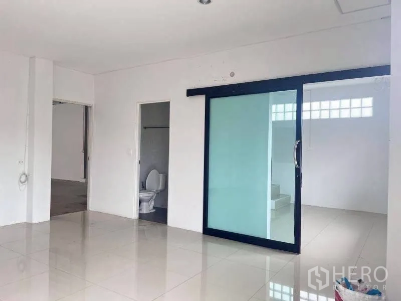 Warehouse for rent in Lam Luk Ka, Pathum Thani - Office space with a frosted glass sliding partition and an adjacent restroom.