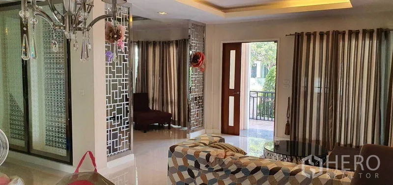 Detached House for sale in Khan Na Yao, Bangkok - Living area view with decorative mirrored screens and wooden front door opening to the terrace.
