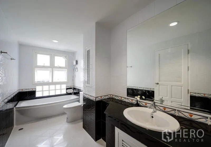 Townhouse for sale - Spacious bathroom with bathtub, black-and-white tiles and a wide mirror.