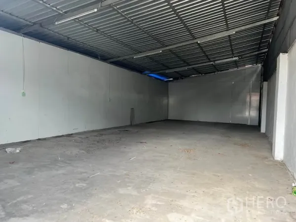 Warehouse for rent in Mueang Samut Prakan, Samut Prakan - Empty warehouse interior with concrete floor, high metal roof, and white insulated walls.