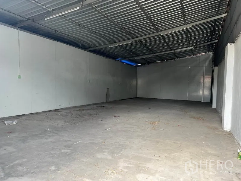 Warehouse for rent in Mueang Samut Prakan, Samut Prakan - Empty warehouse interior with concrete floor, high metal roof, and white insulated walls.
