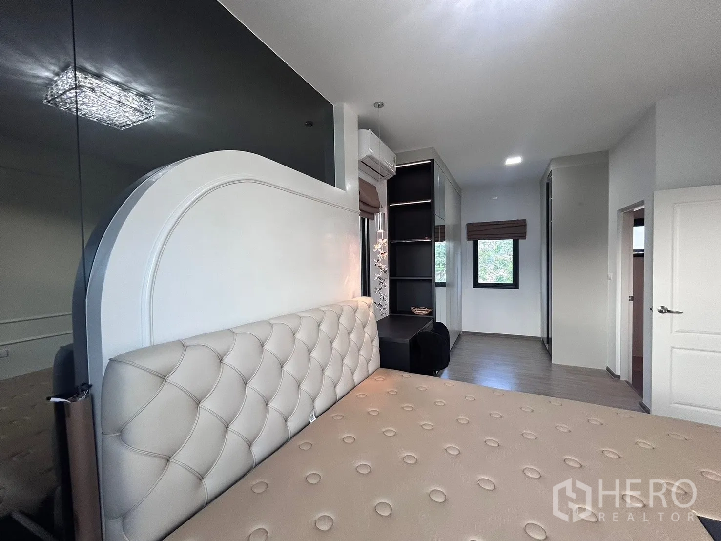 Semi-detached House for rent in Bang Phli, Samut Prakan - Master bedroom view showing tufted headboard, work desk with shelves, and side window.