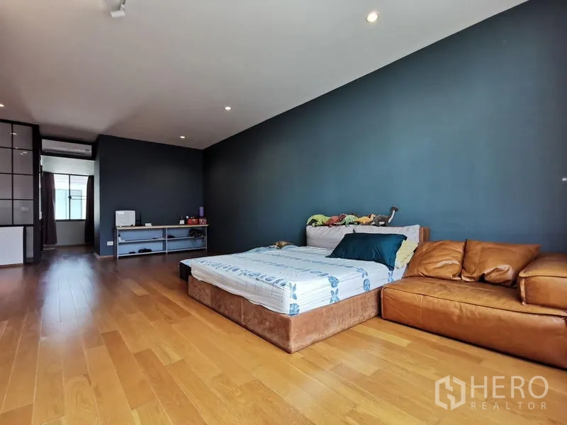 Townhouse for sale - Large bedroom with dark accent wall, bed and leather sofa on wooden flooring.