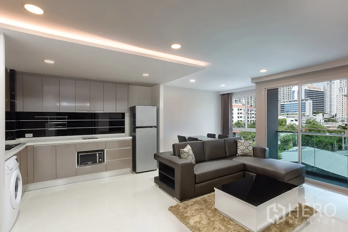 คอนโด for rent in Khlong Toei, Bangkok - พื้นที่นั่งเล่นแบบโอเพ่นแพลน โซฟาเข้ามุม ชุดทานข้าว ระเบียง และครัวบิลท์อิน.