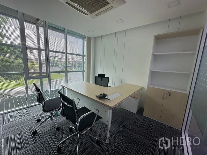 Office Space for rent - Corner executive office with floor-to-ceiling windows, desk, visitor chairs and built-in shelving.