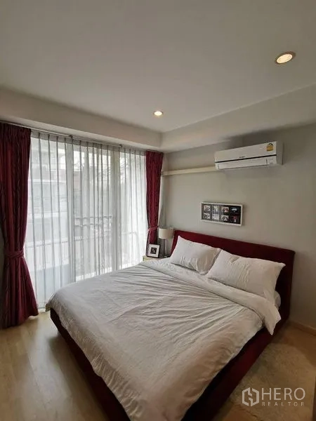 Townhouse for rent or sale in Yan Nawa, Bangkok - Primary bedroom with large window, sheer curtains, red headboard and balcony access.
