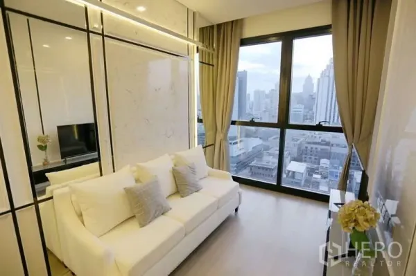 公寓 出租在Watthana, Bangkok - 采光充足的客厅，白色沙发、仿大理石墙面与落地窗俯瞰阿索克天际线