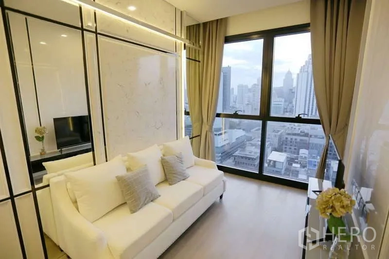 公寓 出租在Watthana, Bangkok - 采光充足的客厅，白色沙发、仿大理石墙面与落地窗俯瞰阿索克天际线
