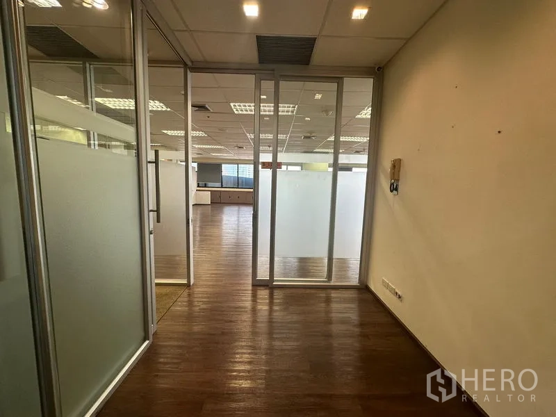 Office Space for rent in Bang Rak, Bangkok - Entrance to a glass-partitioned office with frosted panels and wood flooring.