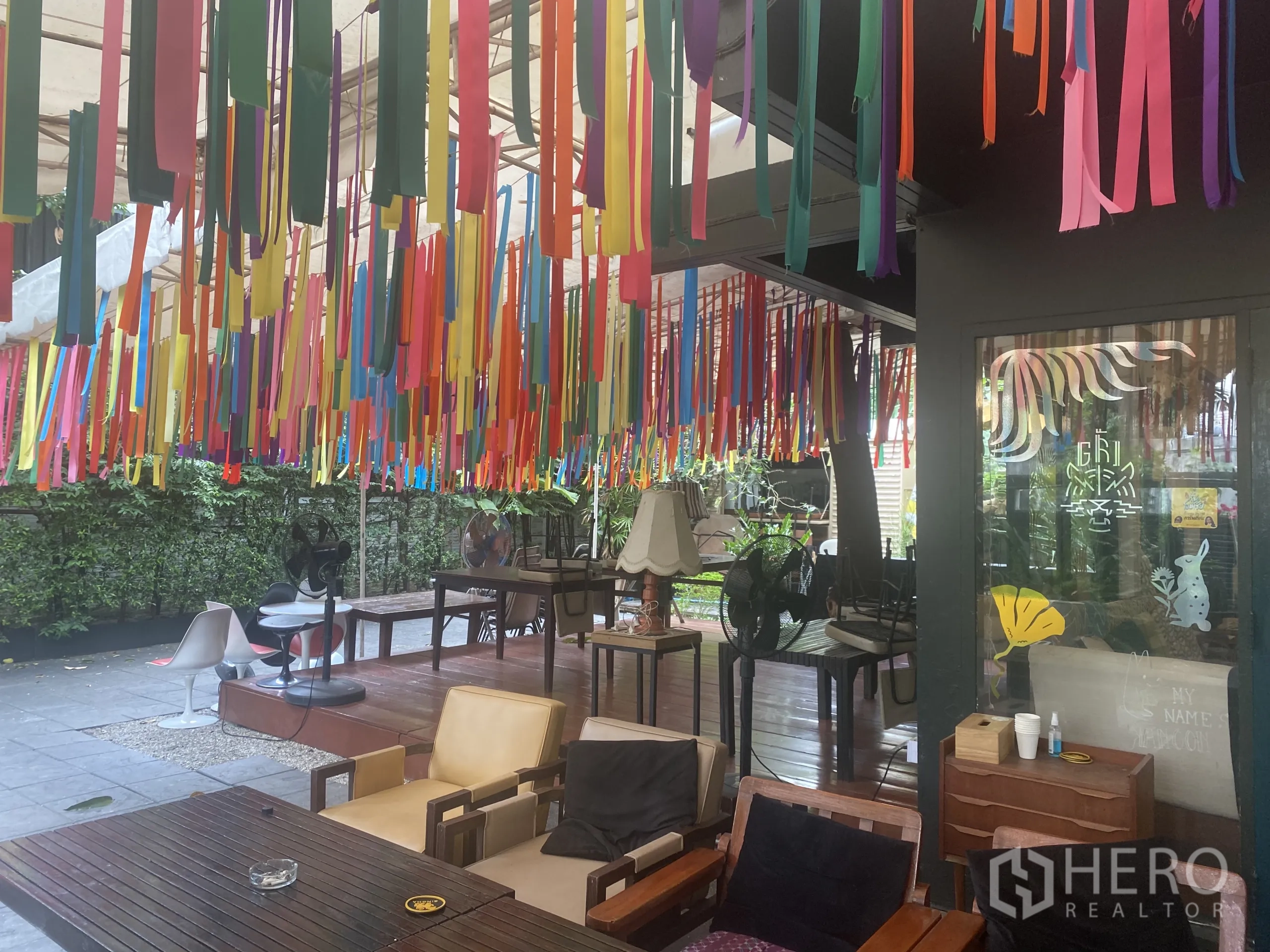 Retail Space for rent in Watthana, Bangkok - Covered patio with colorful ribbons, wooden tables and lush greenery.