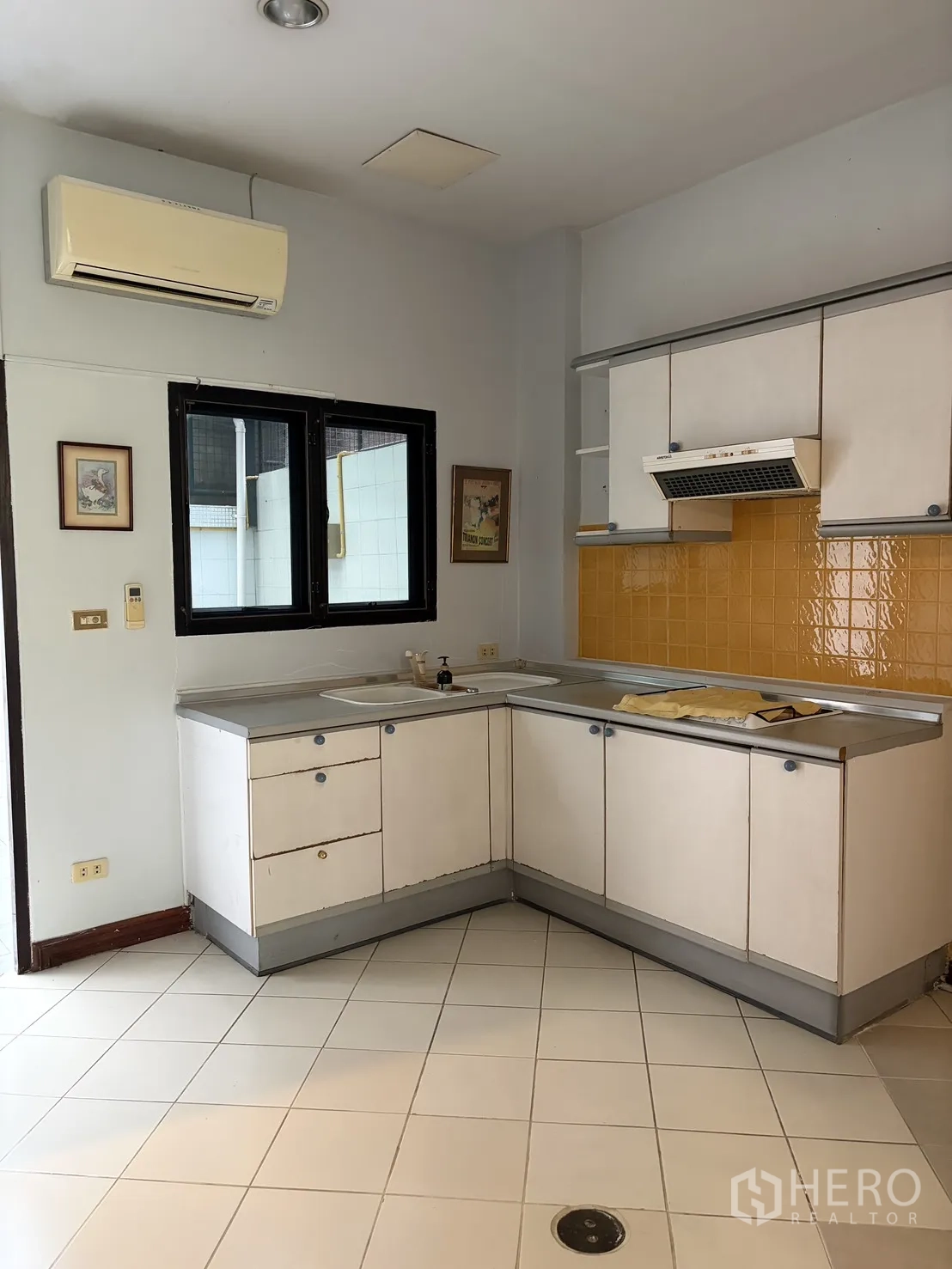 โฮมออฟฟิศ for rent in Watthana, Bangkok - ครัวรูปตัวแอลพร้อมตู้สีขาว ผนังกระเบื้องสีเหลือง และพื้นกระเบื้อง