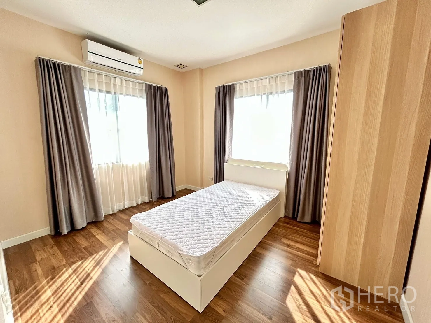 独栋房屋 for rent or sale in Prawet, Bangkok - 明亮卧室，单人床，木地板，两扇配窗帘的窗户与壁挂空调。