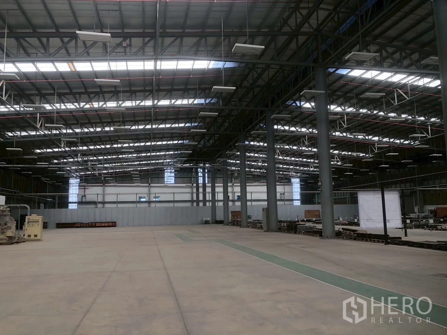 Factory for rent in Pluak Daeng, Rayong - Large production hall with metal columns, roof skylights, and concrete floor.