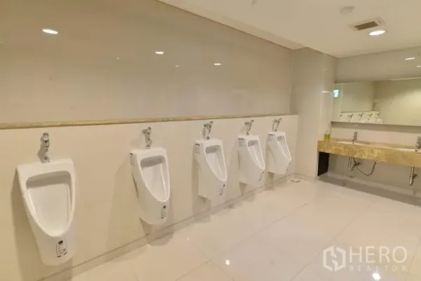 办公空间 出租在Phaya Thai, Bangkok - 明亮男卫，整排小便池与石材台面洗手区。