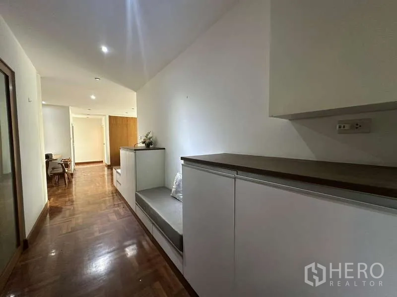 公寓 出租在Watthana, Bangkok - 明亮走廊，拼花木地板，内置白色柜与座椅，通向餐区。