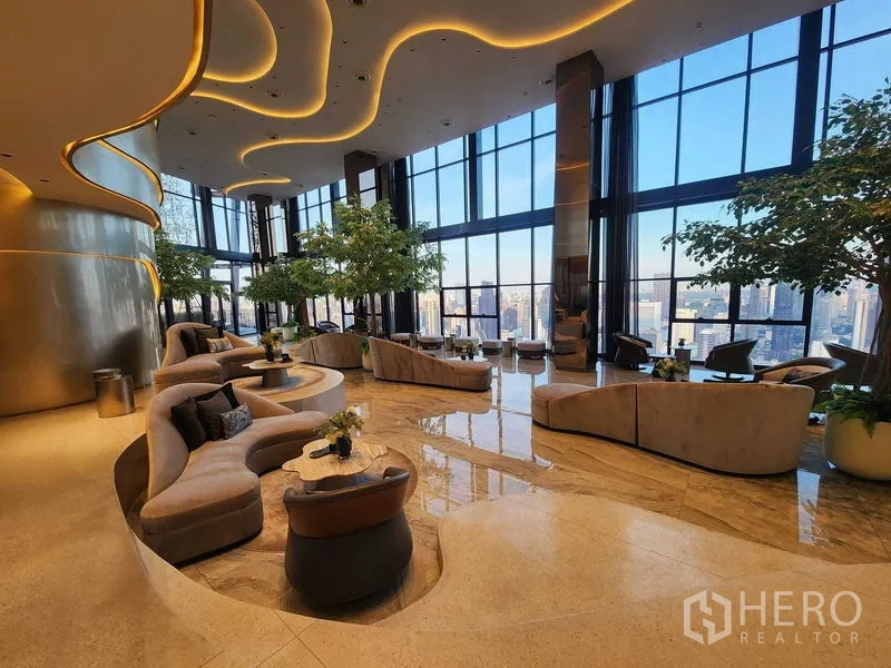 Condominium for rent - Curved ceiling lights above plush lounge area with tall glass walls and city views.