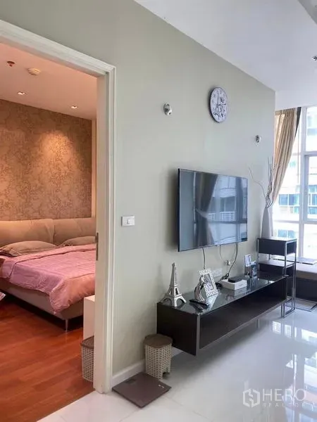 公寓 出租或出售在Bang Kapi, Bangkok - 客厅墙挂电视与电视柜，旁连卧室门，采光良好。