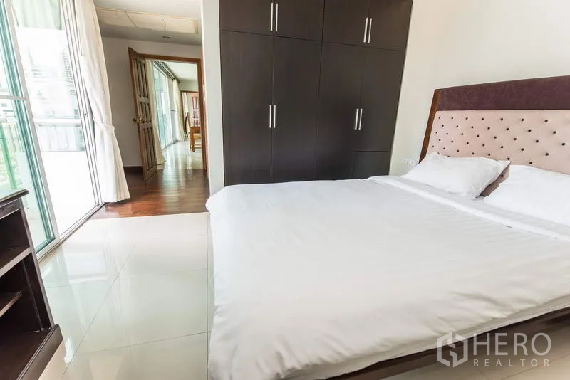 Apartment for rent in Sathon, Bangkok - Secondary bedroom with built-in wardrobe and access to a sunlit balcony.