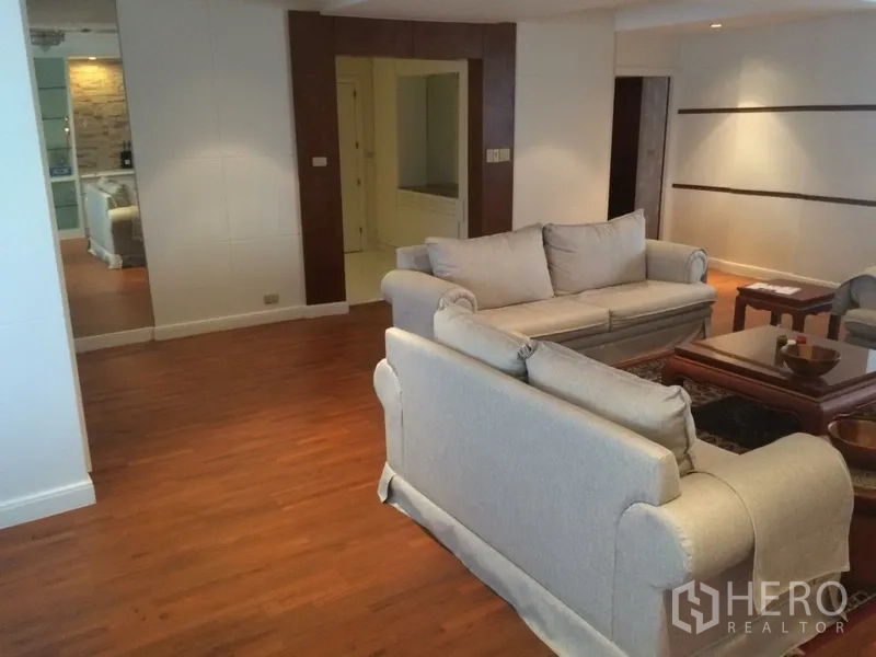 Condominium for rent in Khlong Toei, Bangkok - Wide living space with two sofas on wooden flooring and feature wall details.