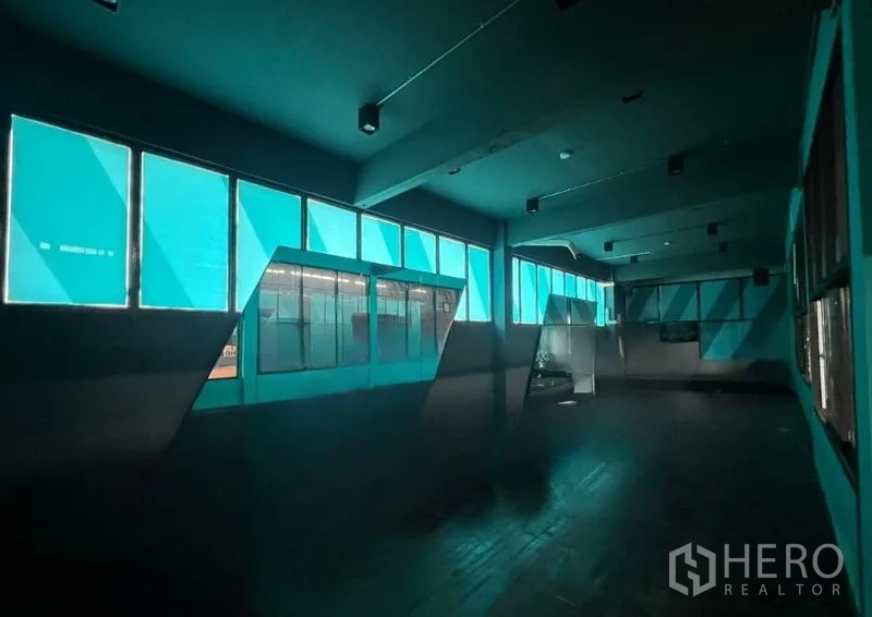 Showroom for rent in Mueang Samut Prakan, Samut Prakan - Dark room with turquoise-tinted windows and geometric wall panels