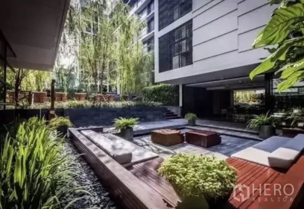 公寓 出租在Watthana, Bangkok - 景观庭院，长椅与绿植点缀，坐落于公寓楼之间