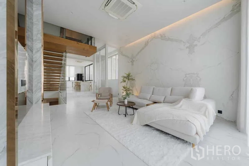 ทาวน์เฮาส์ ให้เช่าหรือขายในWatthana, Bangkok - ห้องนั่งเล่นโอเพ่นแพลน พื้นหินอ่อน โซฟาตัวแอล และบันไดลอยไปยังครัว
