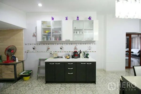 Detached House for rent or sale in Lat Krabang, Bangkok - Pantry area with glass-front wall cabinets and a black base cabinet on patterned tiles.