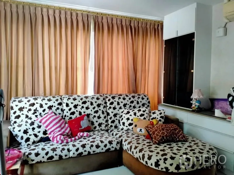 独立式住宅 出售在Thawi Watthana, Bangkok - 温馨起居室，花纹沙发、落地窗帘与展示柜。