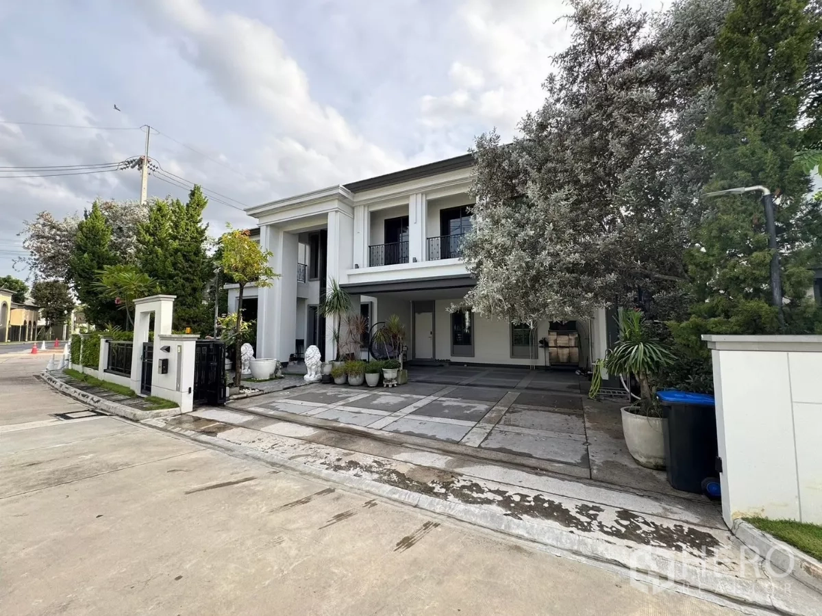 独立式住宅 出售在Mueang Pathum Thani, Pathum Thani - 白色独栋转角地外景，宽阔车道与黑色大门。