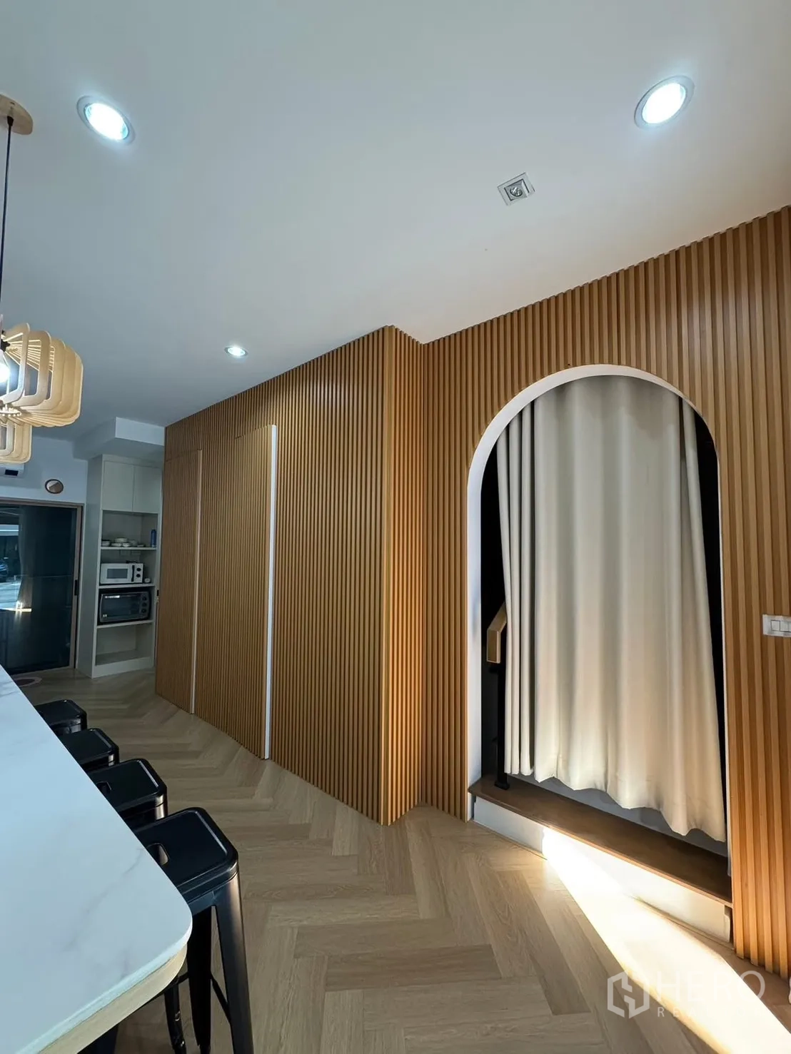 Townhouse for rent in Saphan Sung, Bangkok - Hall with vertical wood slat wall and arched doorway curtain.