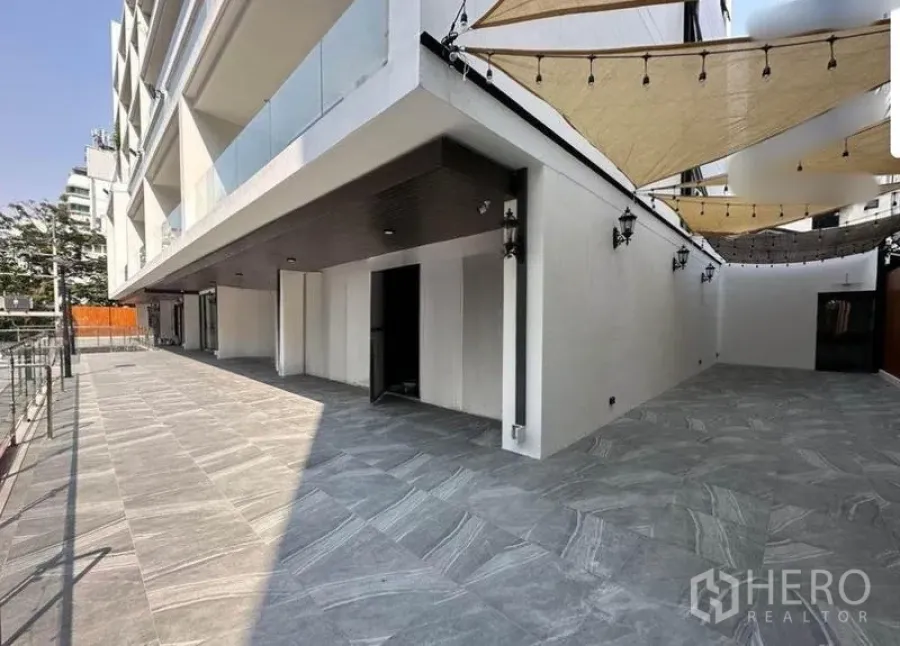 Retail Space for rent - Wide tiled terrace with sail shades and an open shop entrance at a modern retail complex in Watthana, Bangkok.